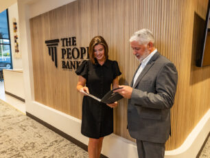 Scott Dunn & Wendy Stafford of Powdersville, SC location standing in front of wall, smiling and discussing banking.